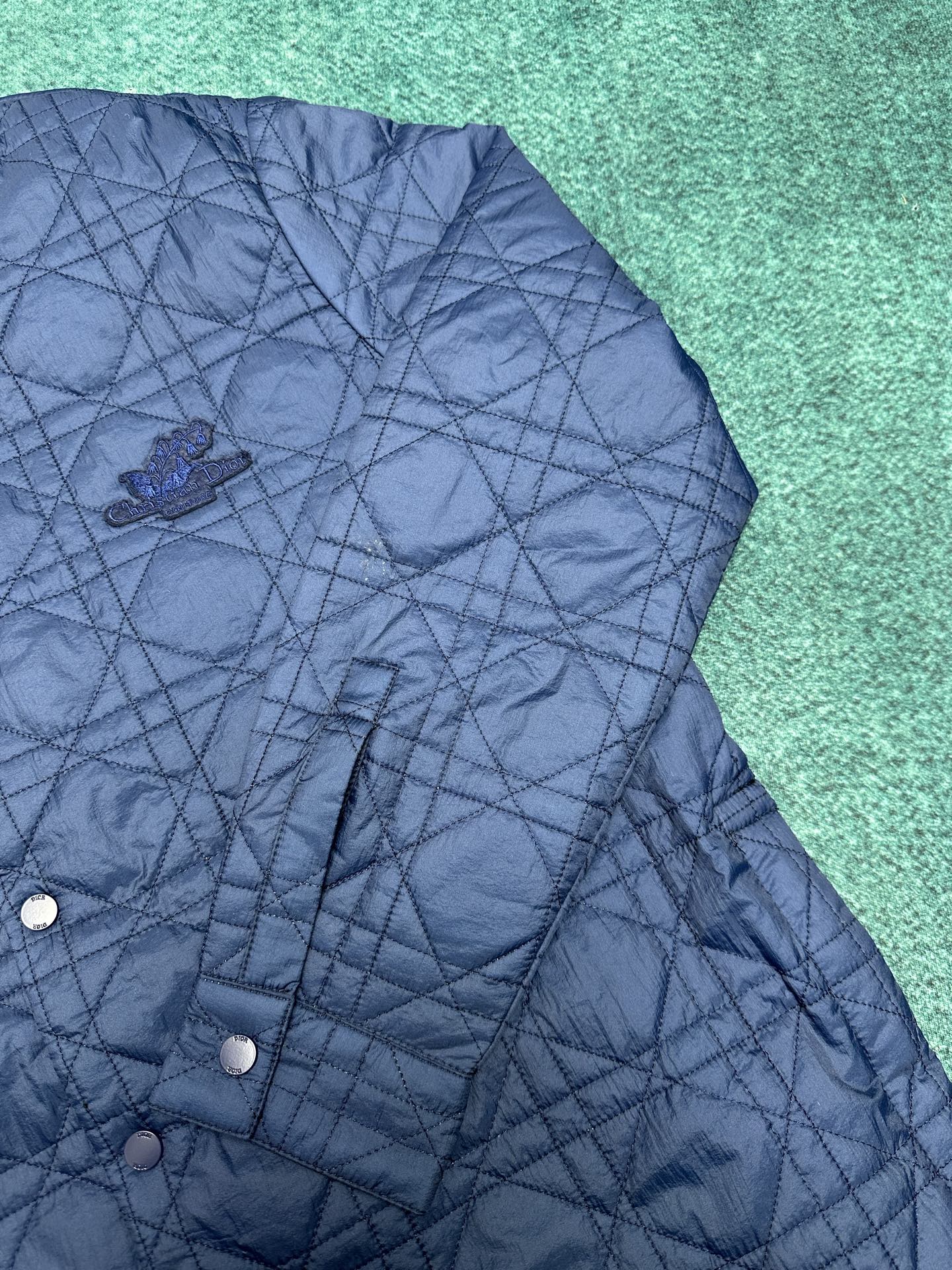 Navy quilted jacket with button placket and embroidered logo patch