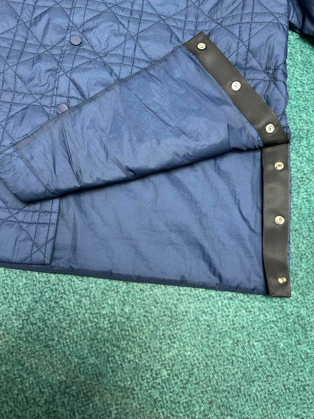 Navy quilted jacket sleeve cuff with dark snap strap detail
