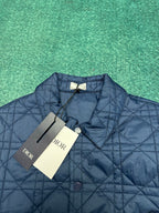 Navy quilted jacket with diamond pattern, logo patch, and attached tags