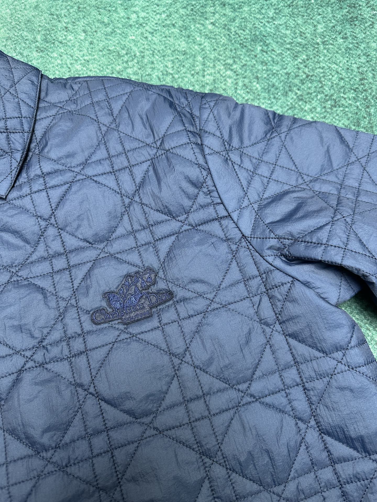 Navy quilted jacket front with small crest logo on chest