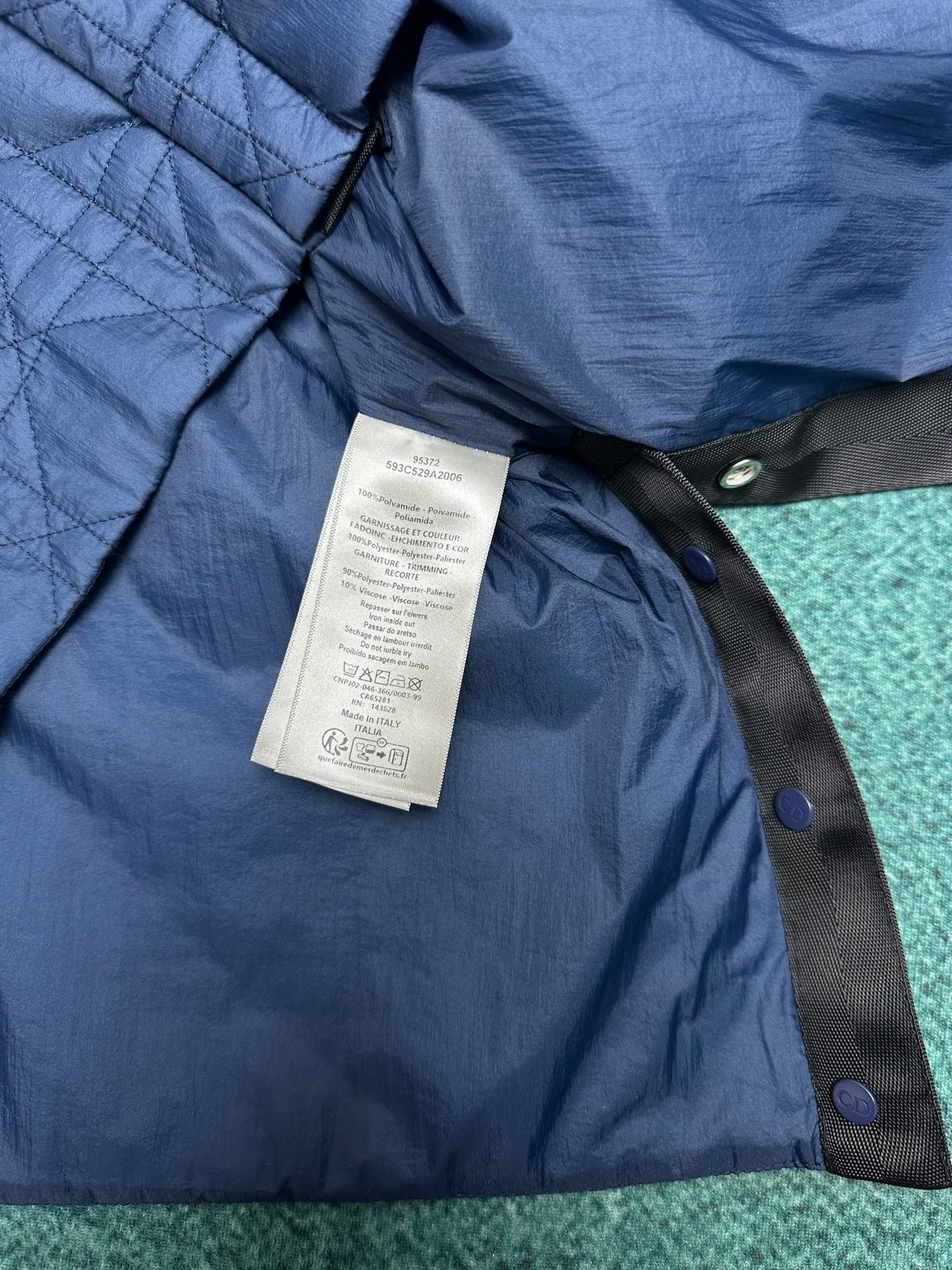 Navy quilted jacket with care label and dark strap button closures
