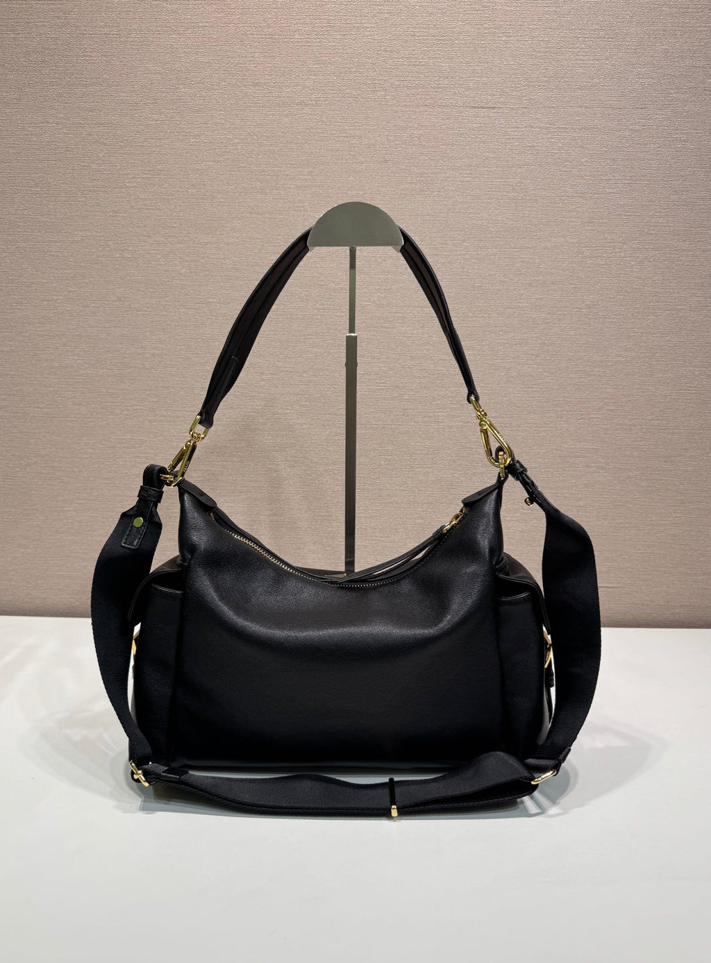 Prada black leather hobo shoulder bag with top handles, gold-tone hardware, and feet.