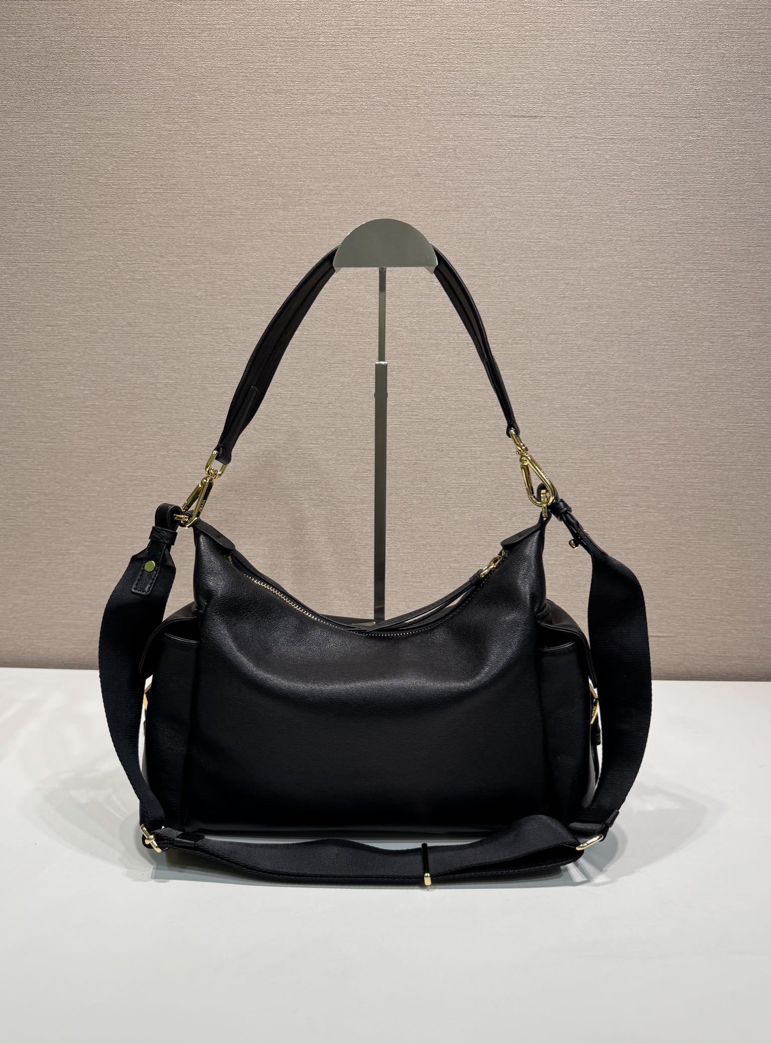 Prada black leather hobo shoulder bag with top handles, gold-tone hardware, and feet.