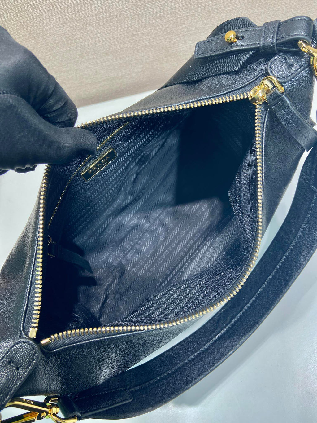 Dark blue Prada shoulder bag interior view with gold zipper and stitched lining.