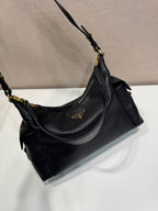 Black Prada shoulder bag angled view with gold-tone rings and slouchy silhouette.