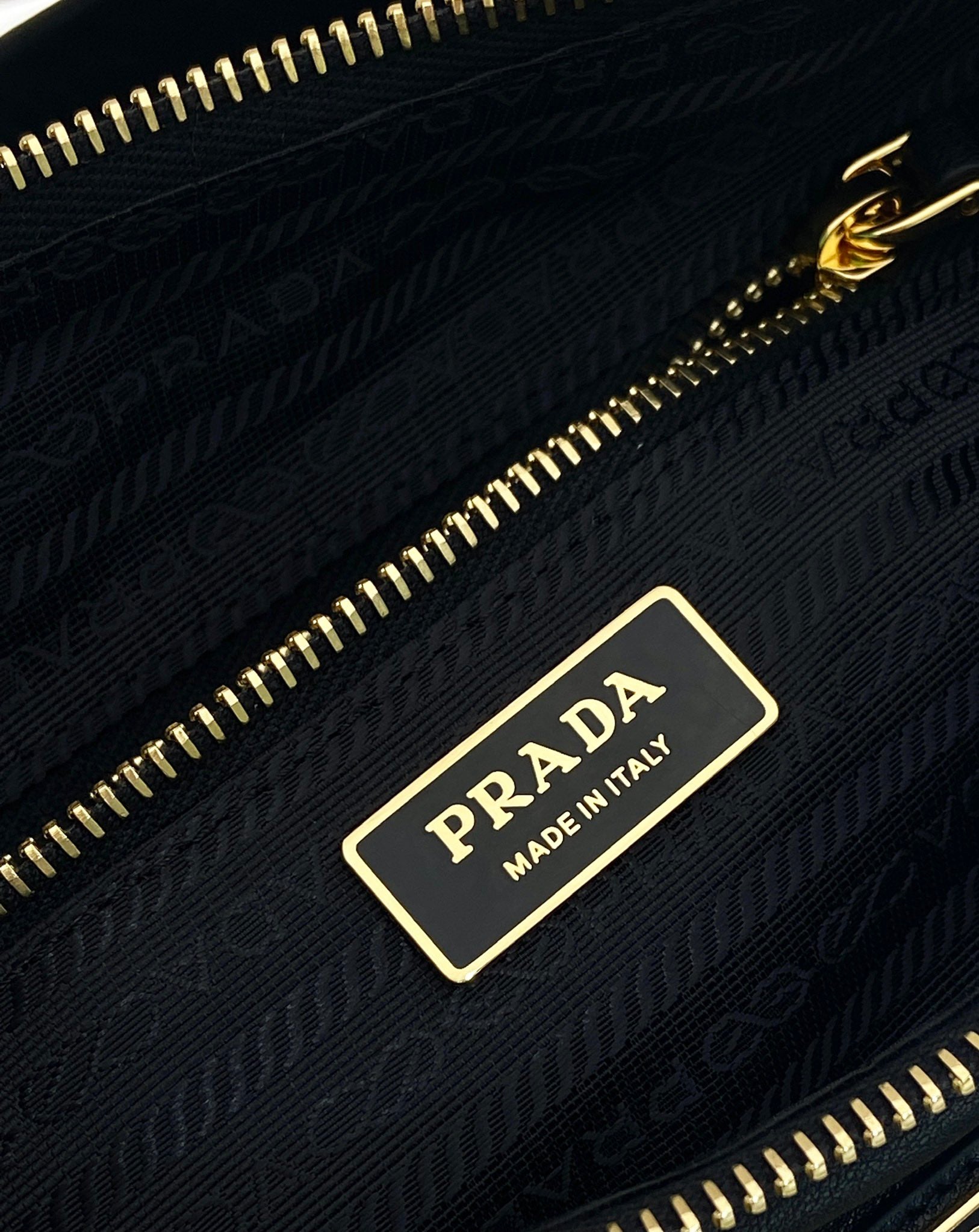 Prada inner logo tag on black fabric lining with gold zipper track.