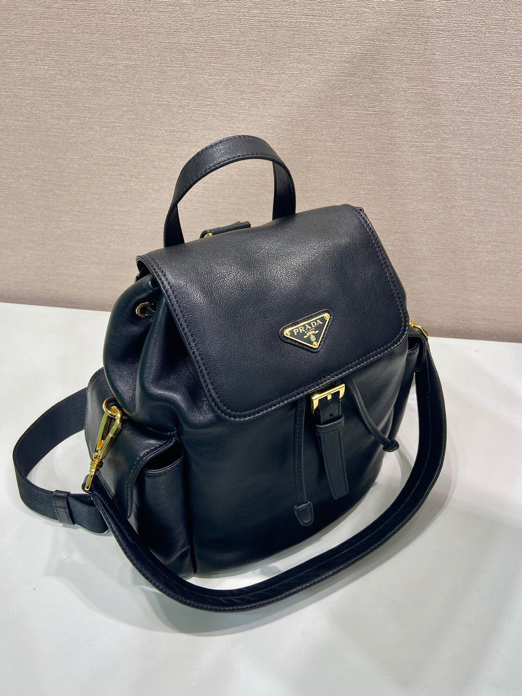 Prada dark blue mini backpack with flap, top handle, and adjustable shoulder strap