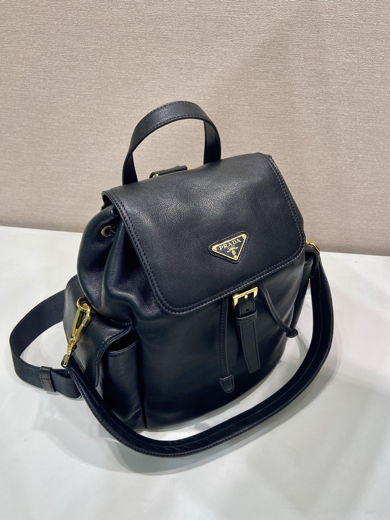 Prada dark blue mini backpack with flap, top handle, and adjustable shoulder strap