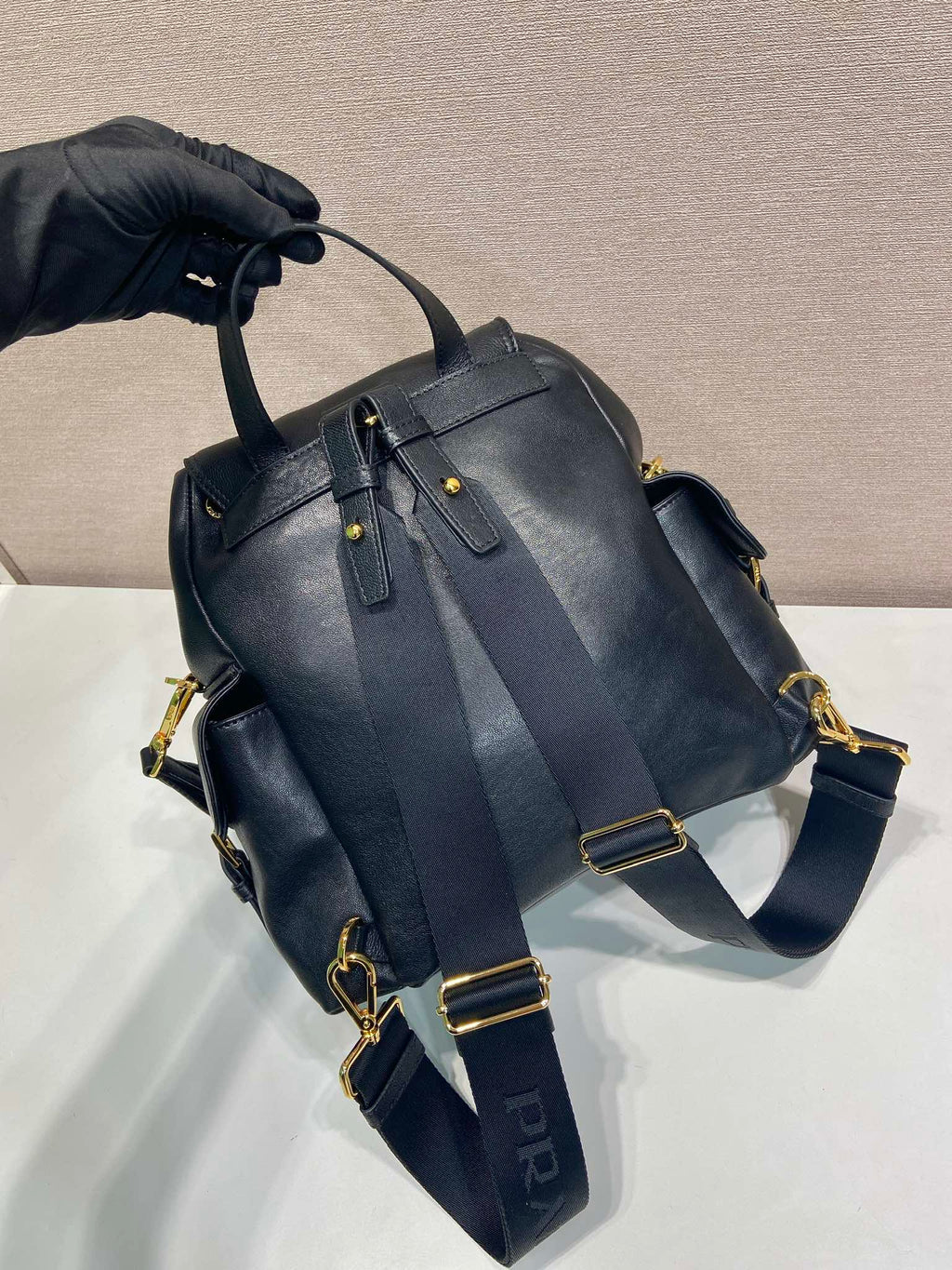 Prada dark blue mini backpack with slouchy top, buckled straps, and gold hardware