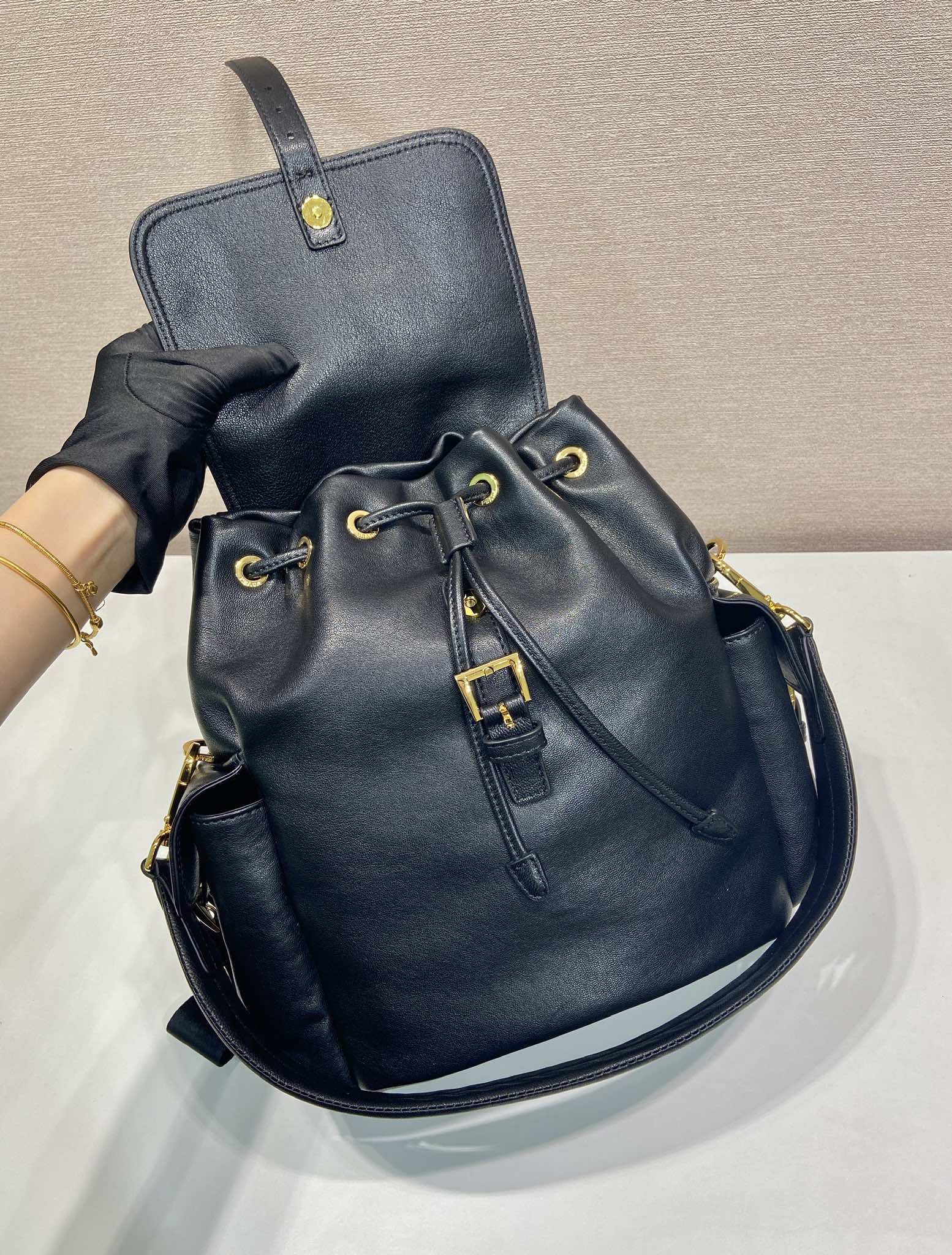 Prada dark blue mini backpack with top handle, front cords, and gold hardware