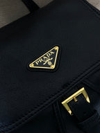 Prada logo patch on dark leather mini bag with gold buckle strap detail