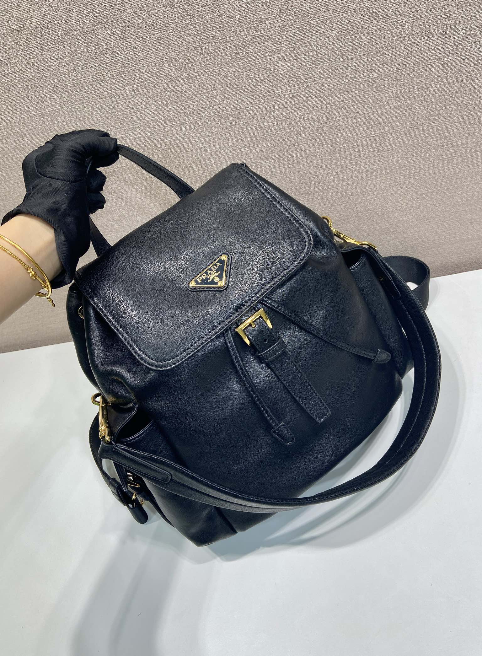 Prada dark blue mini backpack with flap, side zip pocket, and gold hardware