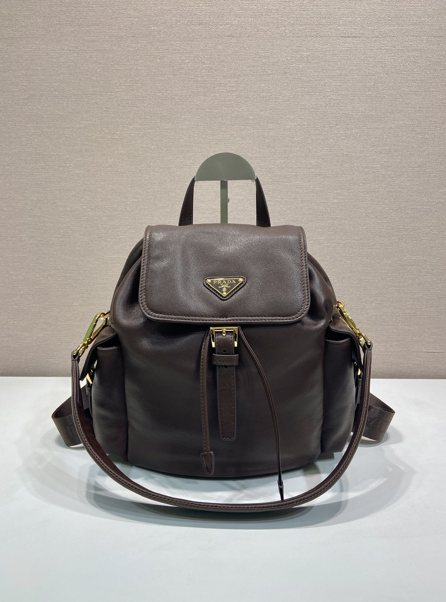 Leather mini backpack with flap front, gold-tone logo, and adjustable shoulder straps