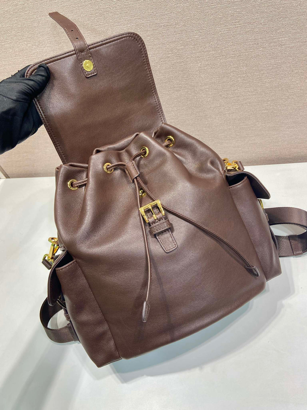 Brown leather mini backpack with drawstring detail and front flap pocket