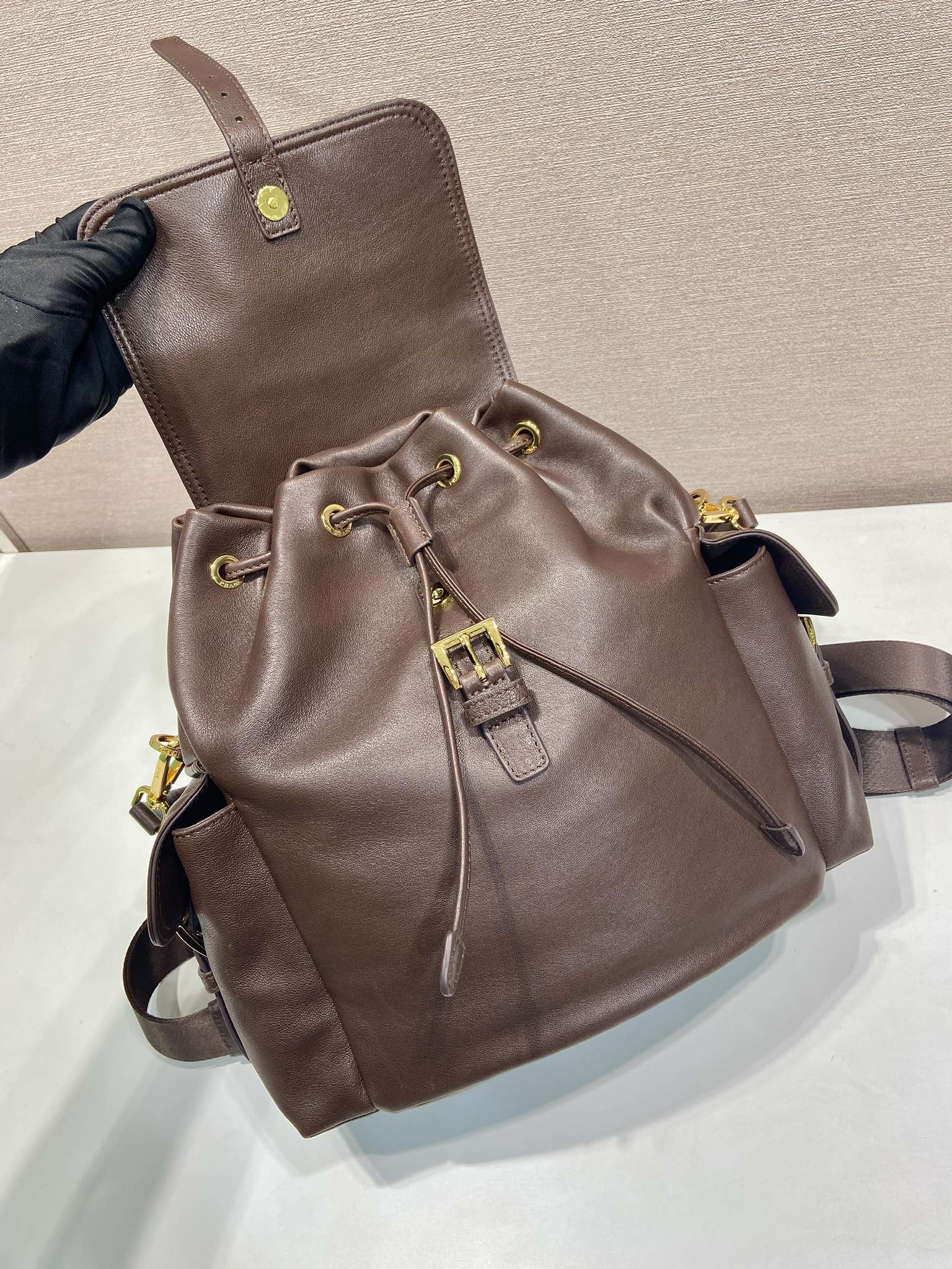 Brown leather mini backpack with drawstring detail and front flap pocket