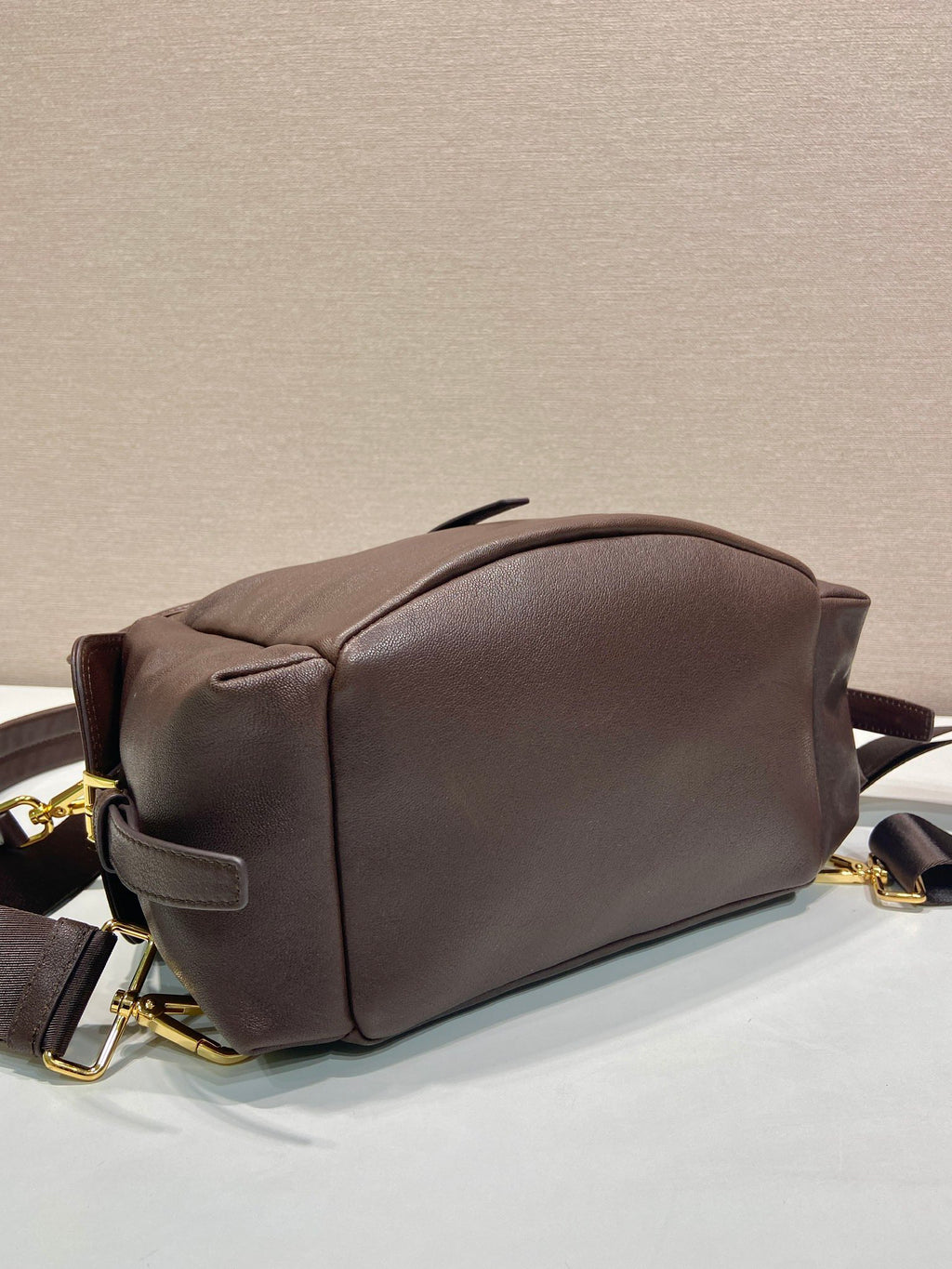 Brown leather mini backpack back view with curved top and gold-tone zipper pulls