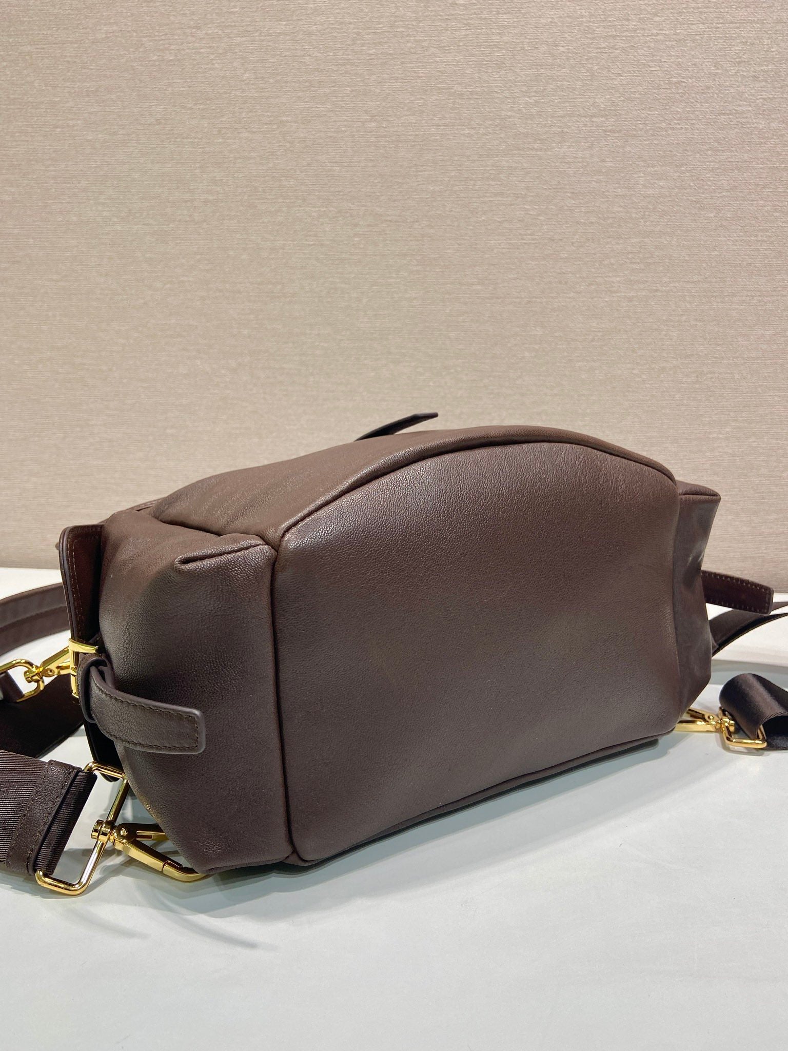 Brown leather mini backpack back view with curved top and gold-tone zipper pulls