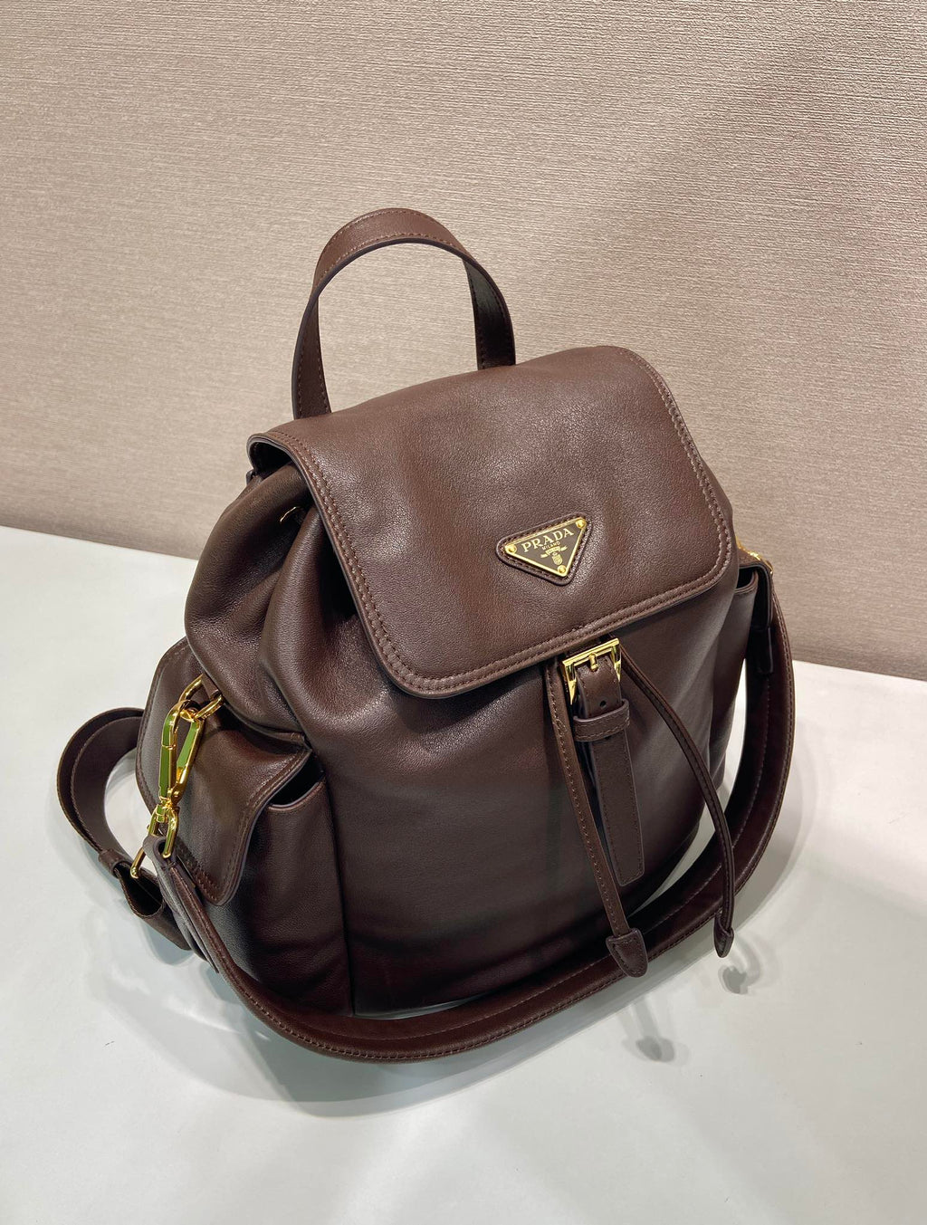 Brown leather mini backpack with flap front, gold-tone hardware, and side zipper pocket