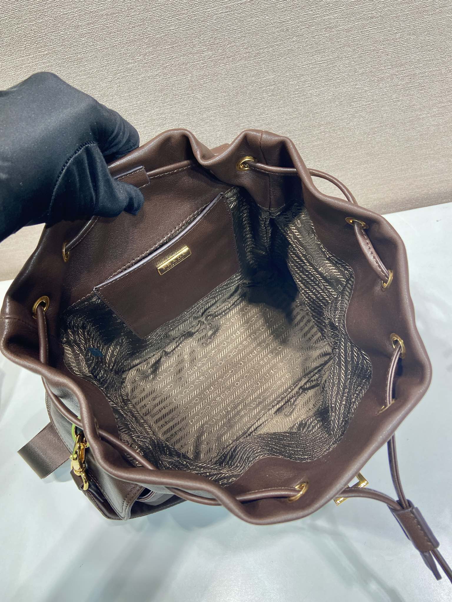 Brown leather mini backpack with open top and patterned interior lining
