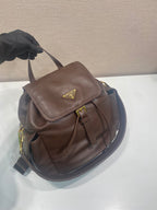 Brown leather mini backpack with flap and strap, shown from upper side angle