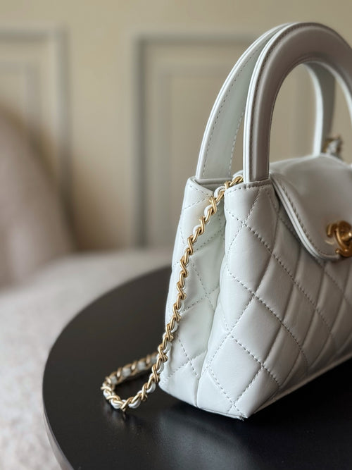 Chanel quilted mini handbag in white, side view with gold chain shoulder strap