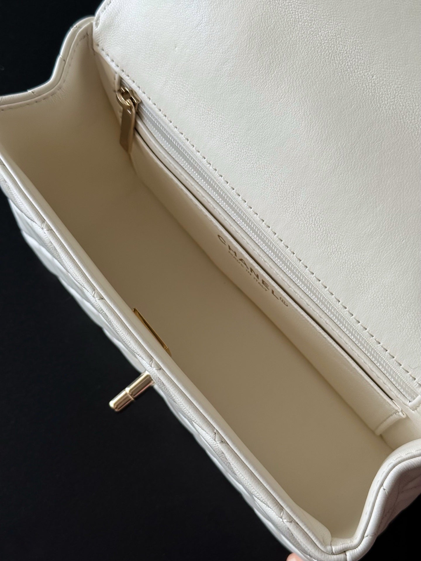 Chanel white quilted mini bag interior view with zip closure and strap
