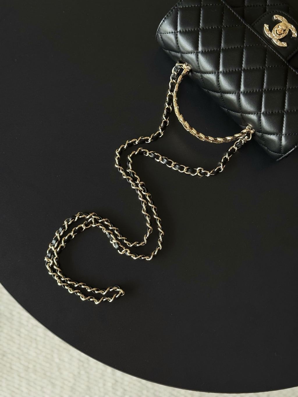 Chanel quilted bag top and chain detail, black with gold-tone logo.