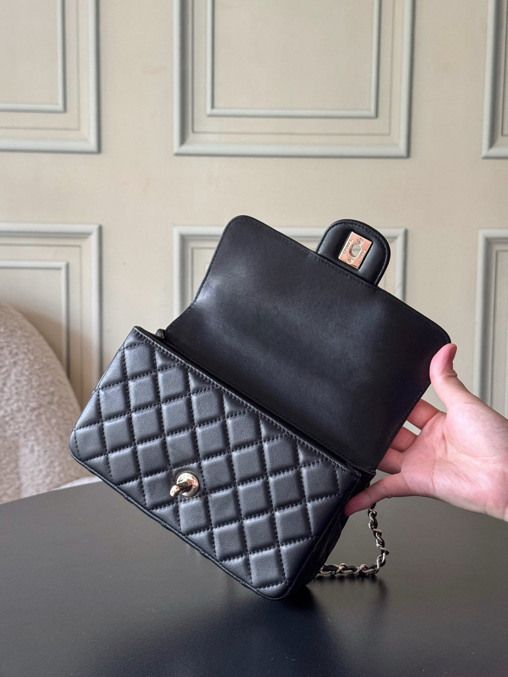 Chanel quilted bag with black top and checkered body, chain strap, gold logo.