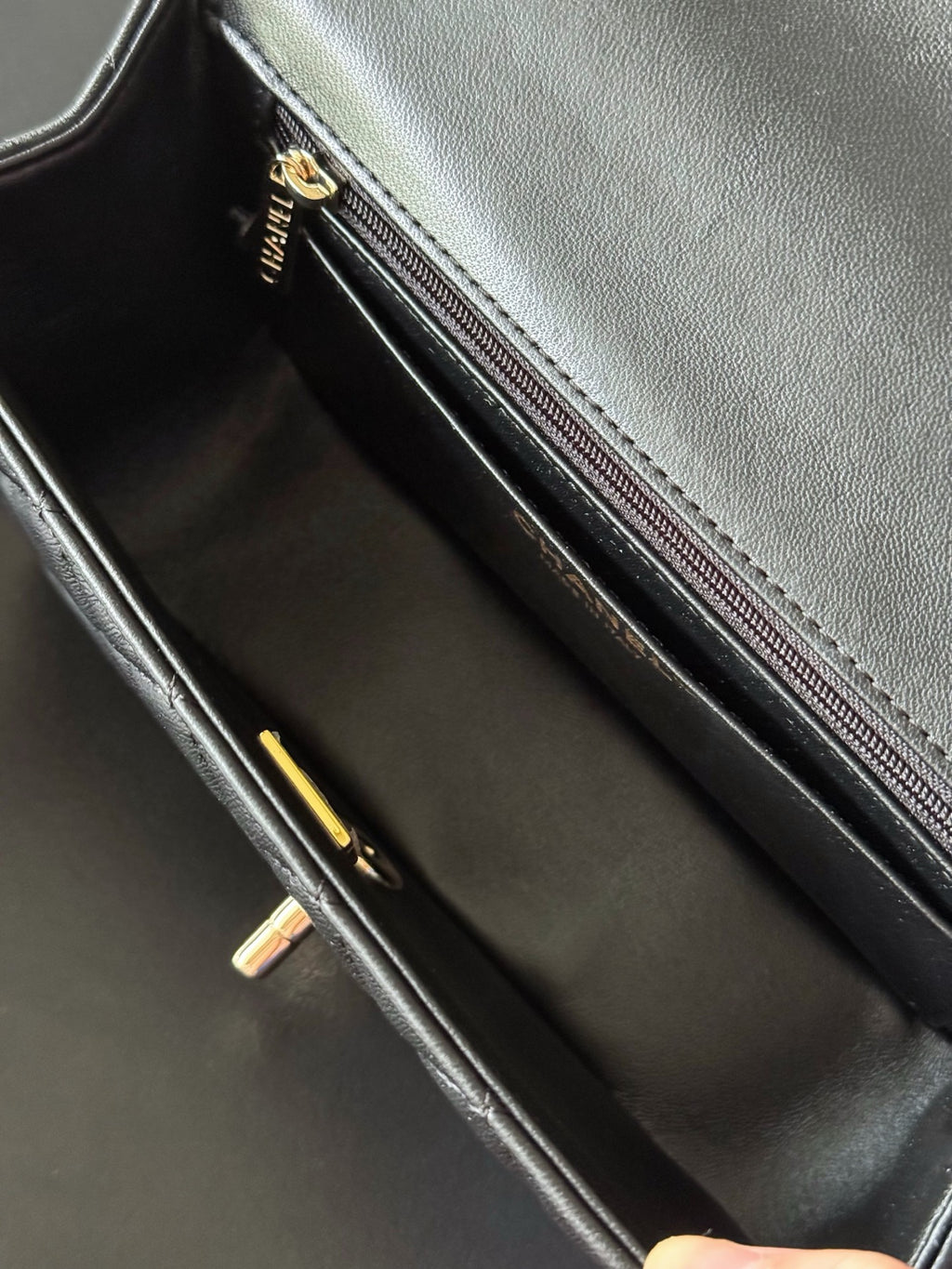 Chanel bag interior view with black lining and long zip pocket, gold hardware.