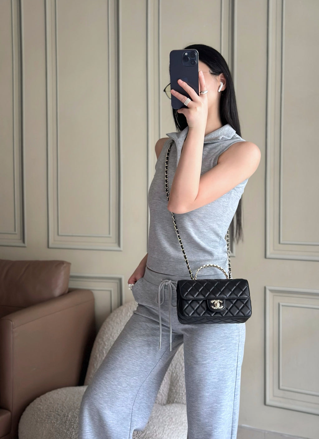 Chanel quilted bag on chain strap, black, worn on shoulder by a person.