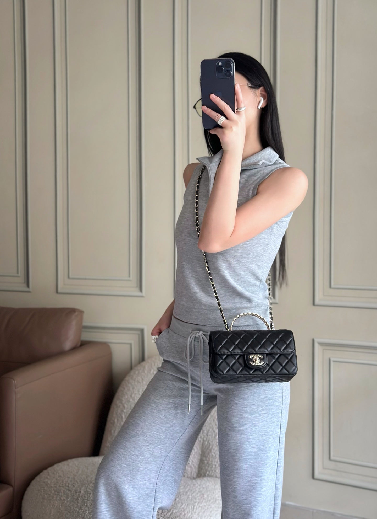 Chanel quilted bag on chain strap, black, worn on shoulder by a person.