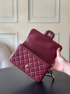Burgundy quilted leather Chanel shoulder bag held in hand, flap and back pocket