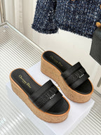 Black platform slide sandals with wide band straps and cork textured sole