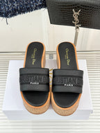 Black platform slide sandals with wide logo band straps and cork footbed