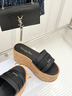 Black platform slide sandals with embossed strap detail and cork wedge sole