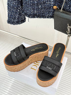 Black platform slide sandals with embossed strap logo and cork wedge heel