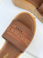 Close-up of brown leather strap sandal with embossed logo across band
