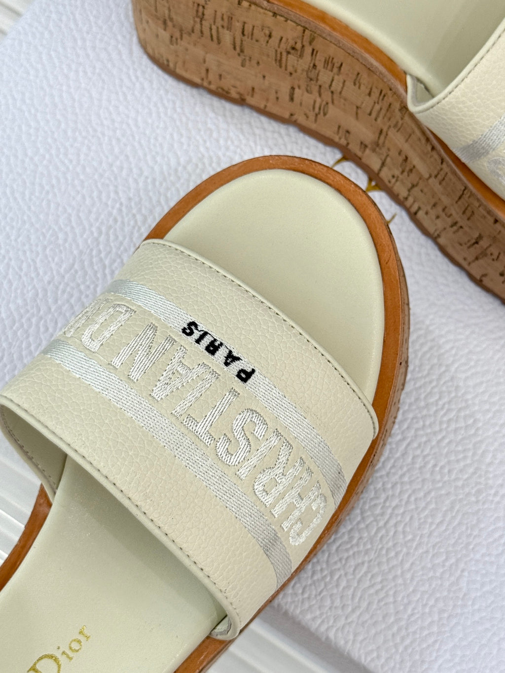 Dior slide sandal close-up of cream strap with embossed logo text