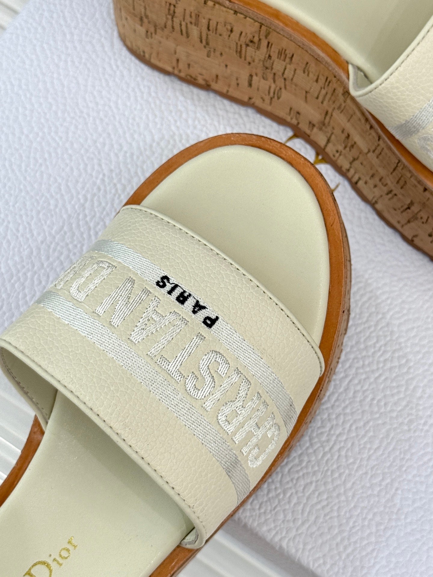 Dior slide sandal close-up of cream strap with embossed logo text