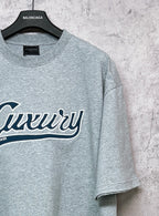 Balenciaga heather gray T-shirt close-up of “Luxury” logo and sleeve