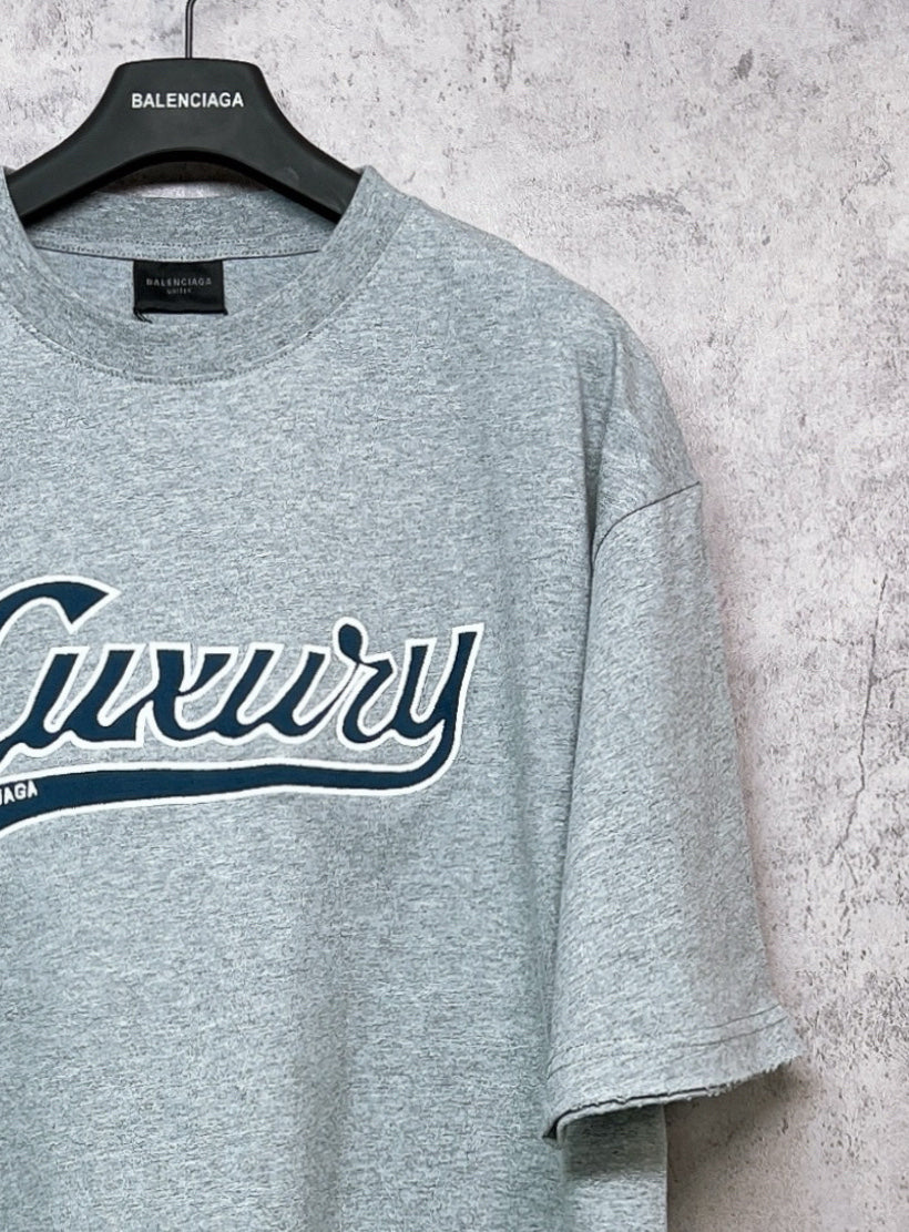 Balenciaga heather gray T-shirt close-up of “Luxury” logo and sleeve