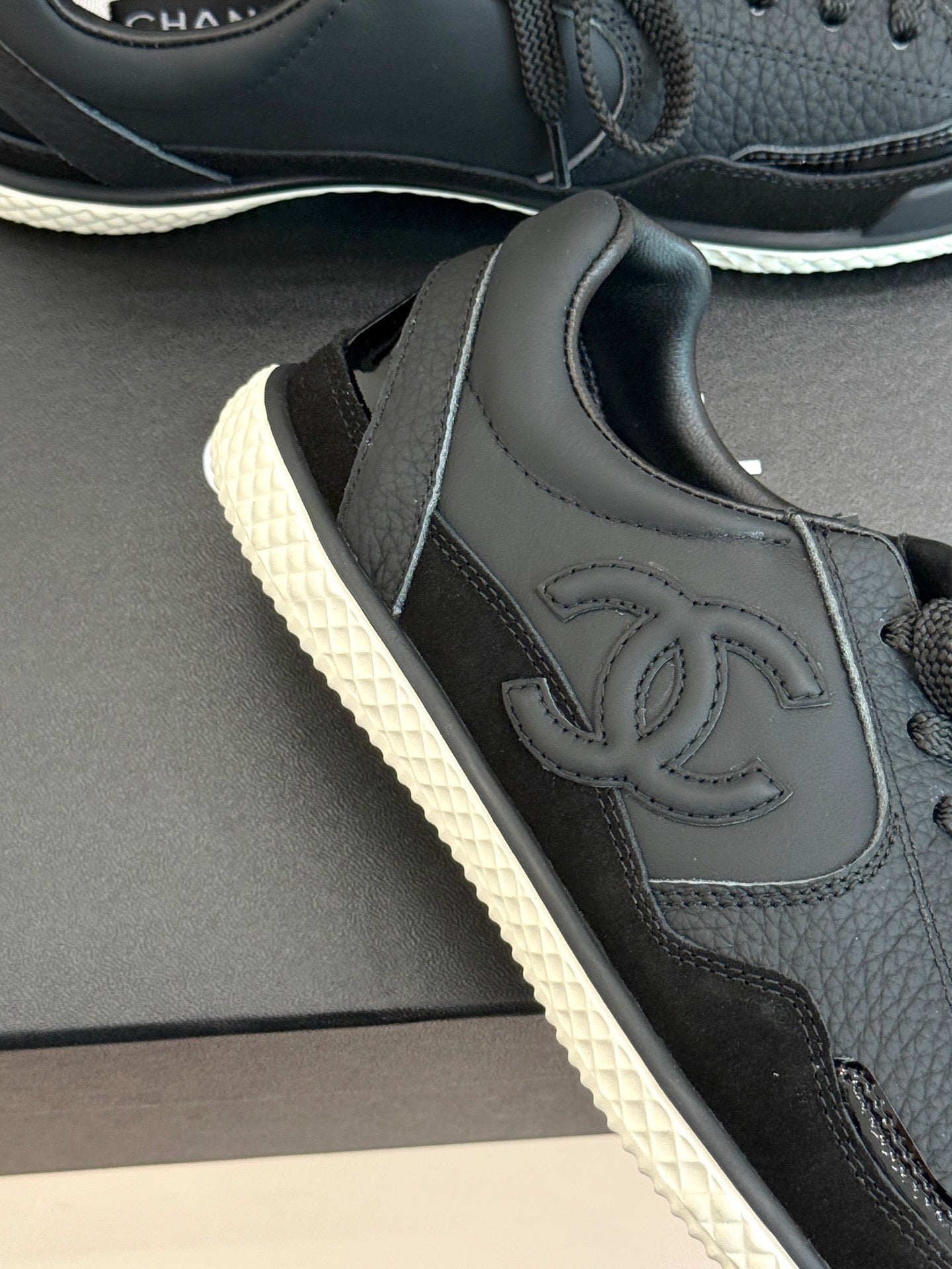 Dark leather sneaker upper with stitched Chanel CC logo and lace eyelets