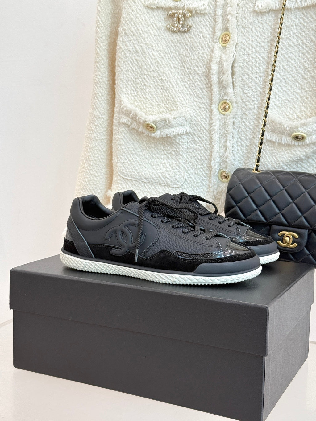 Dark leather lace-up sneakers on box, with Chanel CC logo and textured sole