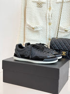 Dark leather lace-up sneakers on box, with Chanel CC logo and textured sole