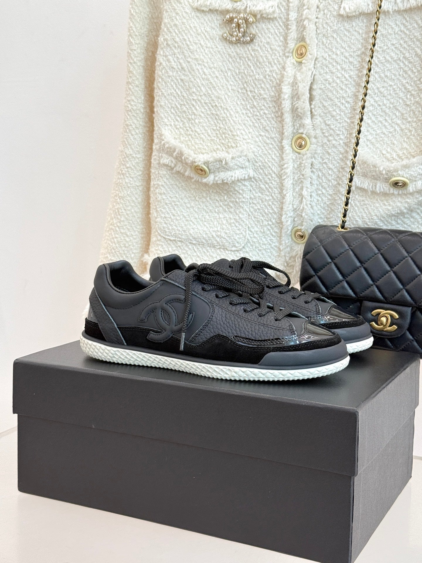 Dark leather lace-up sneakers on box, with Chanel CC logo and textured sole