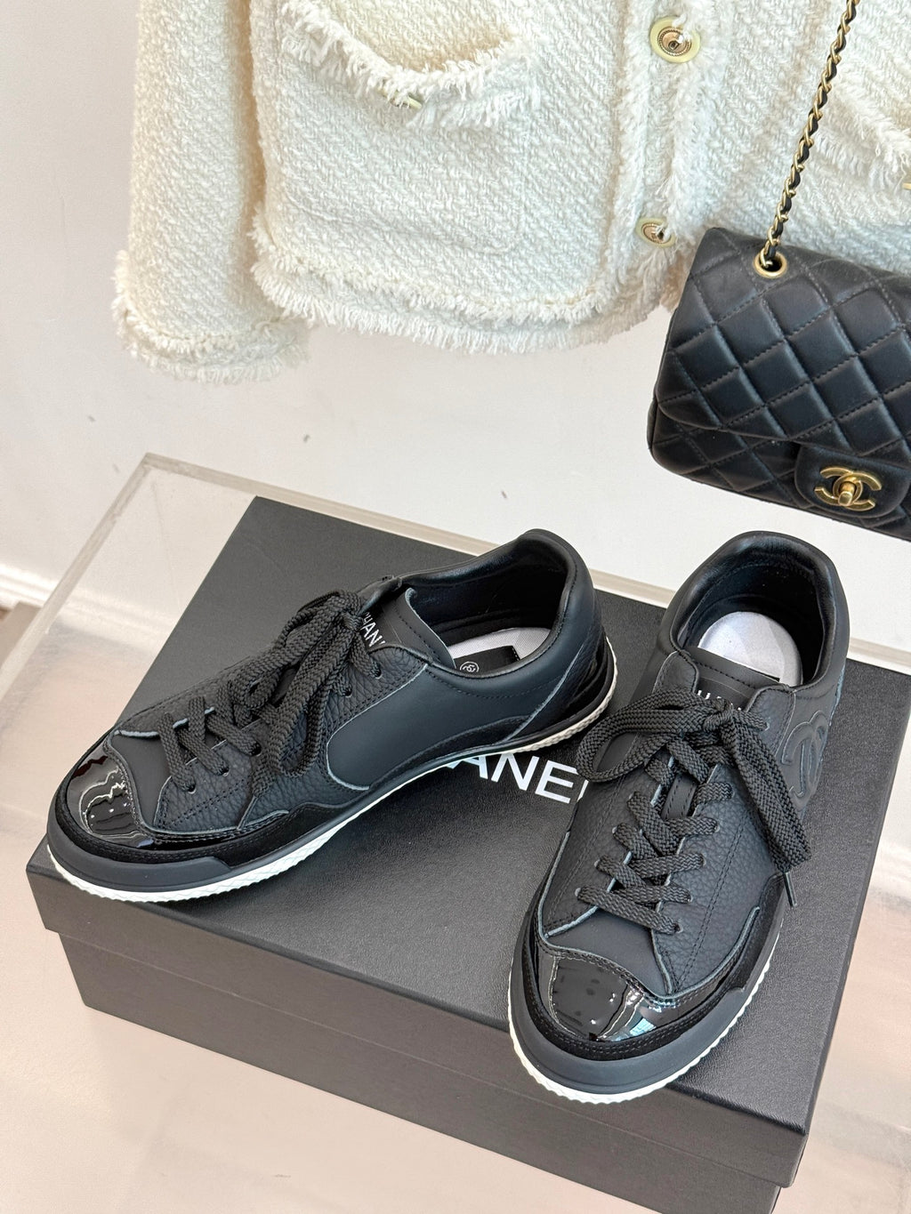 Pair of dark leather lace-up sneakers with Chanel CC logo, on gray shoebox