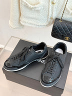 Pair of dark leather lace-up sneakers with Chanel CC logo, on gray shoebox