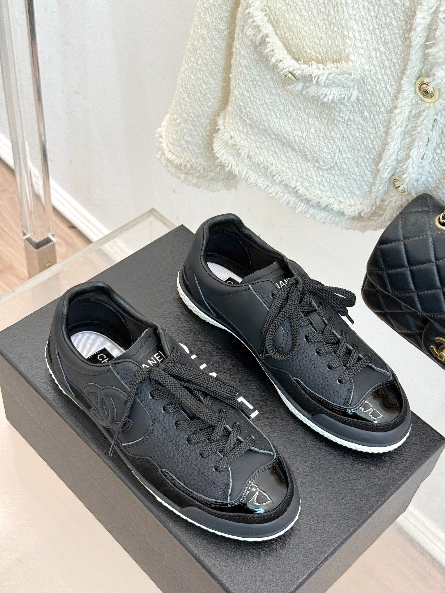 Two dark lace-up sneakers with Chanel CC emblem and white sole trim