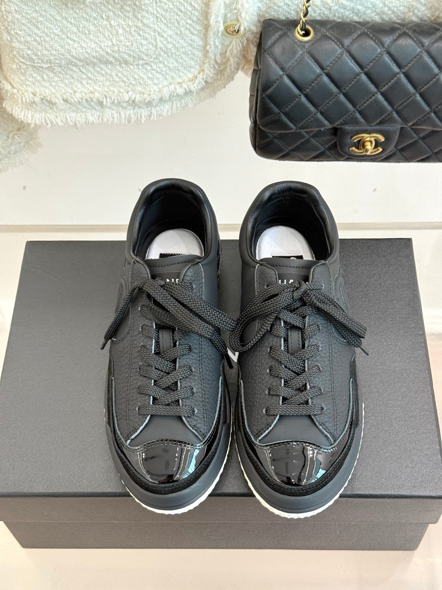 Dark leather lace-up sneakers with Chanel CC emblem and white interior lining