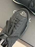 Close-up of dark lace-up sneaker toe with Chanel CC patch and laces
